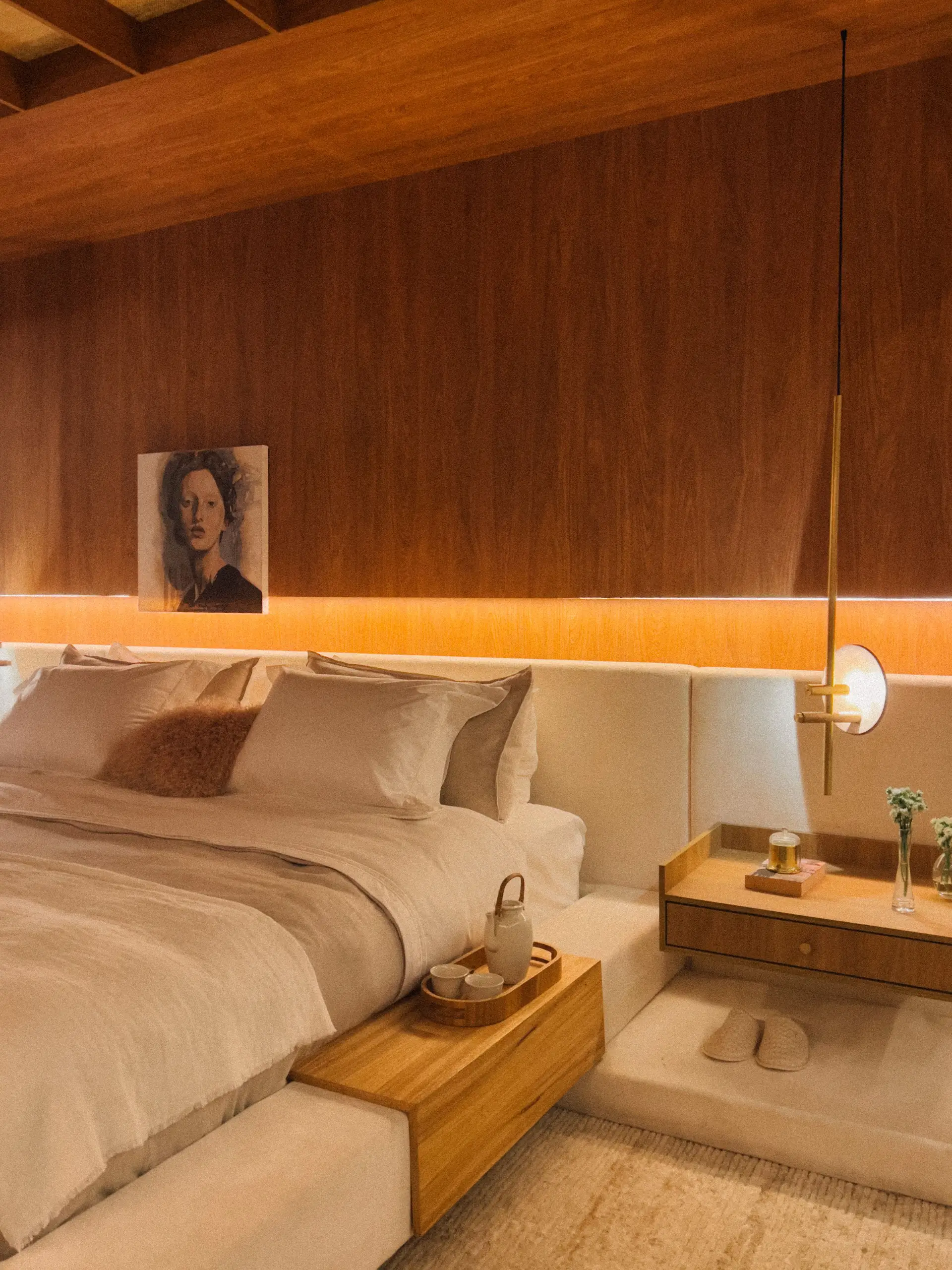 Primary suite bedroom with warm bespoke headboard and textured lime plaster