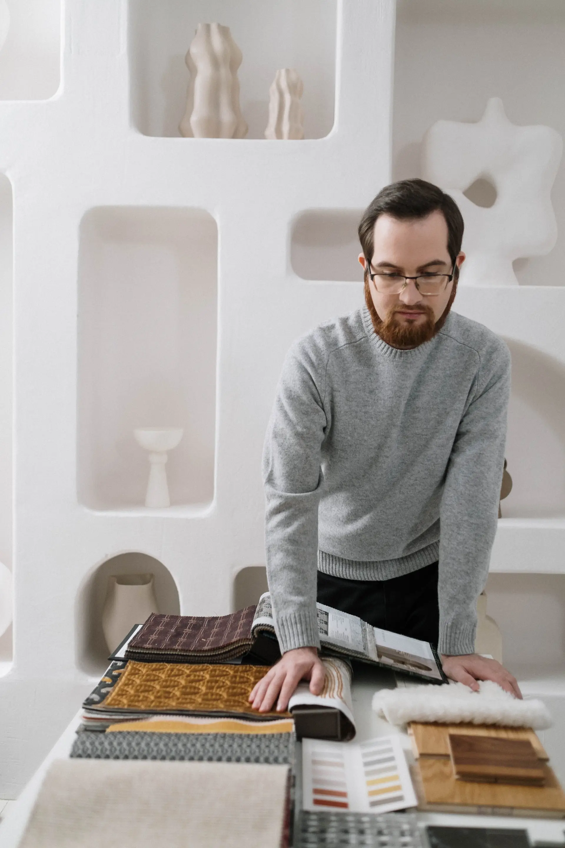 Interior designer considering fabric and material samples in a light-filled studio